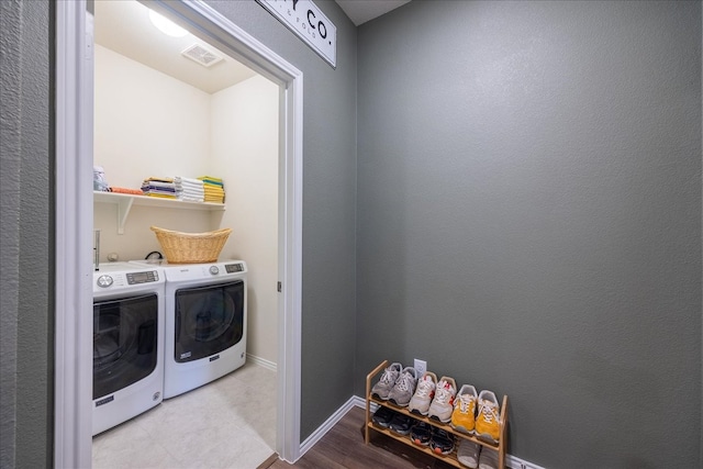 clothes washing area featuring laundry area, baseboards, visible vents, and washer and dryer