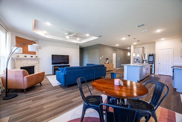 dining area with recessed lighting, dark wood-type flooring, a fireplace, visible vents, and a raised ceiling