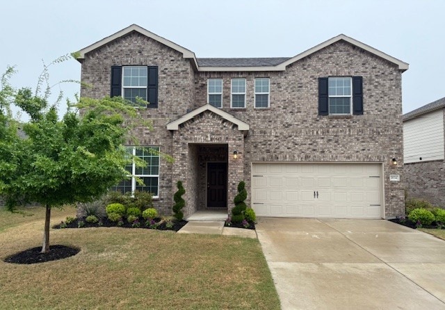 view of front of home featuring an attached garage, concrete driveway, a front lawn, and brick siding