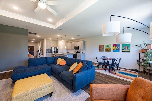 living area with wood finished floors, crown molding, baseboards, a tray ceiling, and ceiling fan