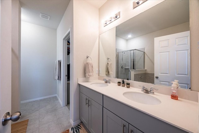bathroom with a tile shower, double vanity, tile patterned flooring, and baseboards