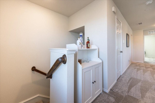 hall with carpet, visible vents, and baseboards