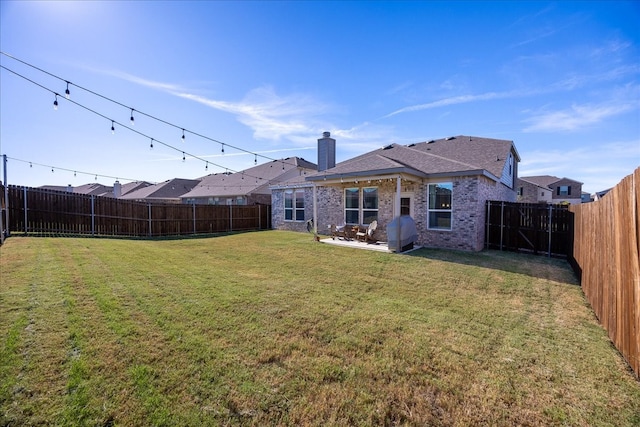 back of property with brick siding, a chimney, a lawn, a patio area, and a fenced backyard