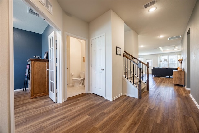 corridor with stairs, visible vents, baseboards, and wood finished floors