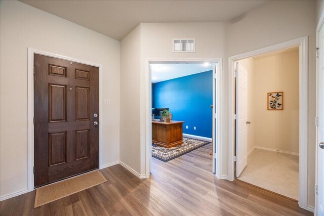 foyer featuring baseboards, visible vents, and wood finished floors