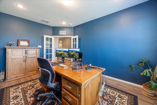 office space with wood finished floors, visible vents, and baseboards