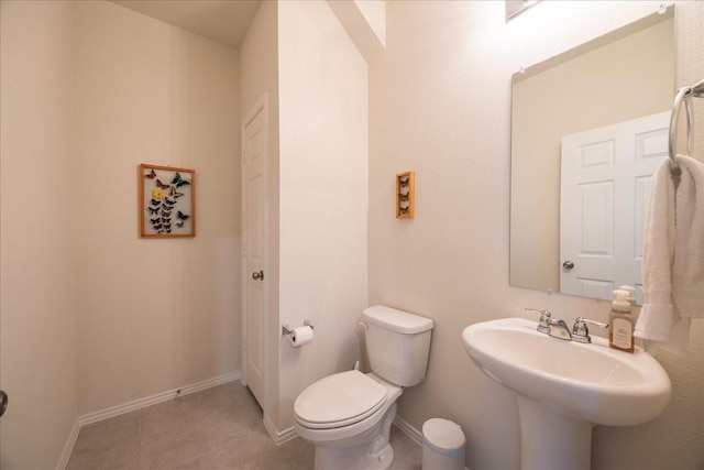 half bath with a sink, toilet, and baseboards
