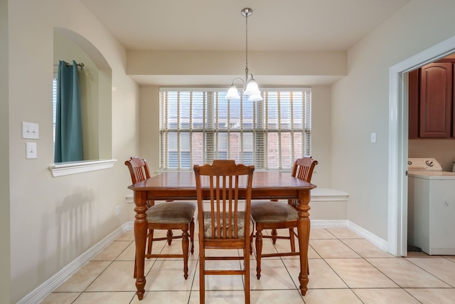 tiled dining space featuring washer / dryer and an inviting chandelier