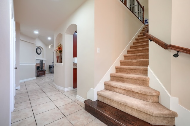 stairway featuring tile patterned flooring and lofted ceiling