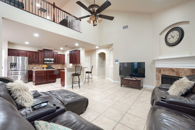 living room featuring high vaulted ceiling, light tile patterned flooring, ceiling fan, and a high end fireplace