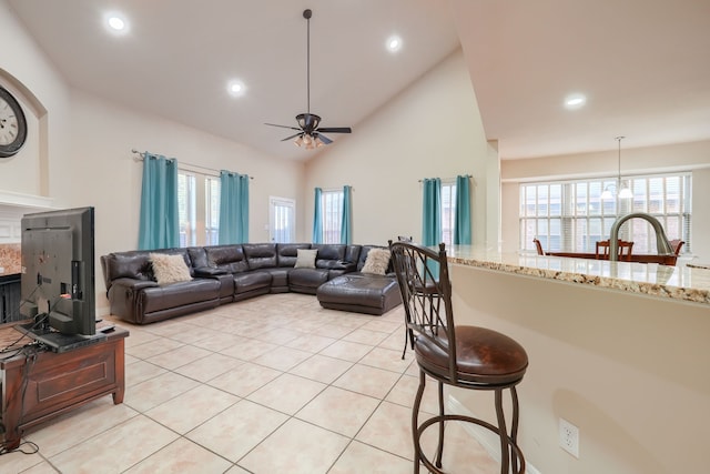 living room featuring ceiling fan, a tile fireplace, light tile patterned floors, and plenty of natural light