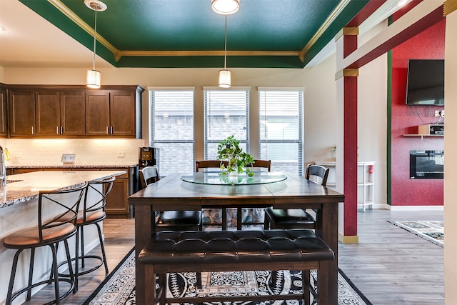 dining room with light wood-type flooring, crown molding, and a tray ceiling