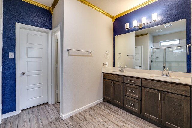 bathroom with ornamental molding, wood-type flooring, vanity, and a shower with shower door