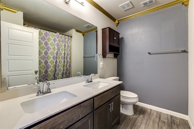 bathroom featuring wood-type flooring, ornamental molding, vanity, a textured ceiling, and toilet