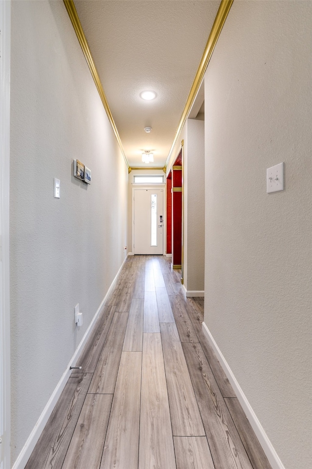 hall with a textured ceiling, crown molding, and light hardwood / wood-style flooring