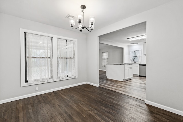 unfurnished dining area featuring a wealth of natural light, dark wood-type flooring, and a notable chandelier