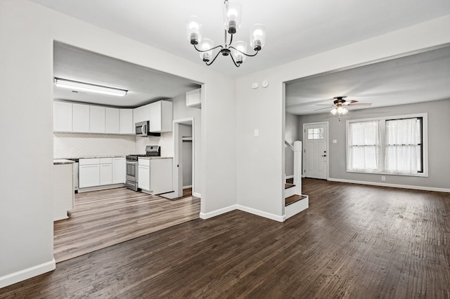 kitchen with white cabinetry, appliances with stainless steel finishes, ceiling fan with notable chandelier, wood-type flooring, and pendant lighting