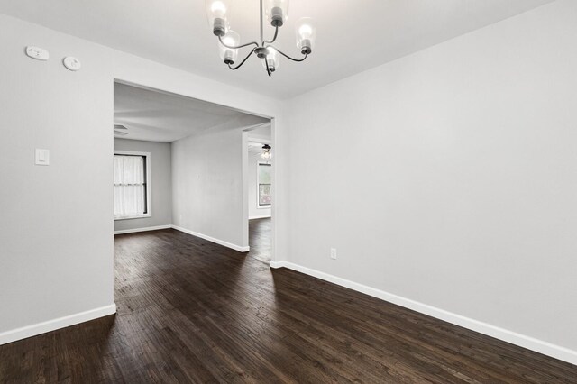 unfurnished dining area featuring dark hardwood / wood-style floors and ceiling fan with notable chandelier