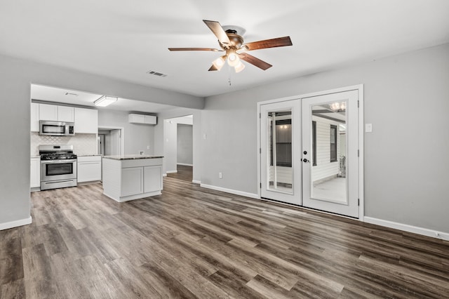 kitchen with tasteful backsplash, french doors, wood-type flooring, stainless steel appliances, and white cabinets