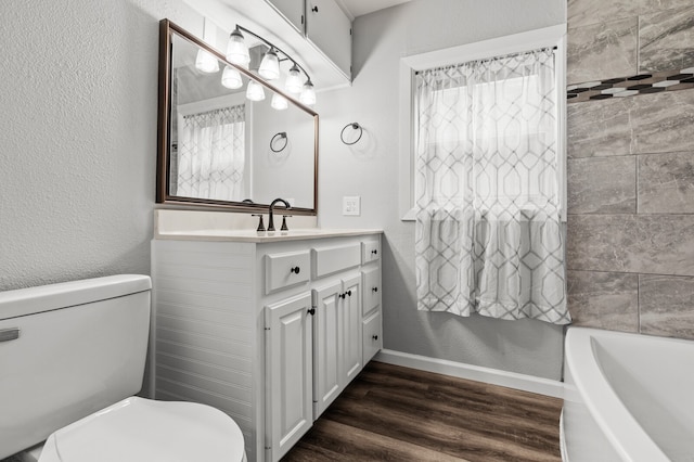 bathroom with toilet, a bath, vanity, and hardwood / wood-style flooring