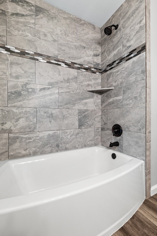 bathroom with tiled shower / bath combo and hardwood / wood-style floors