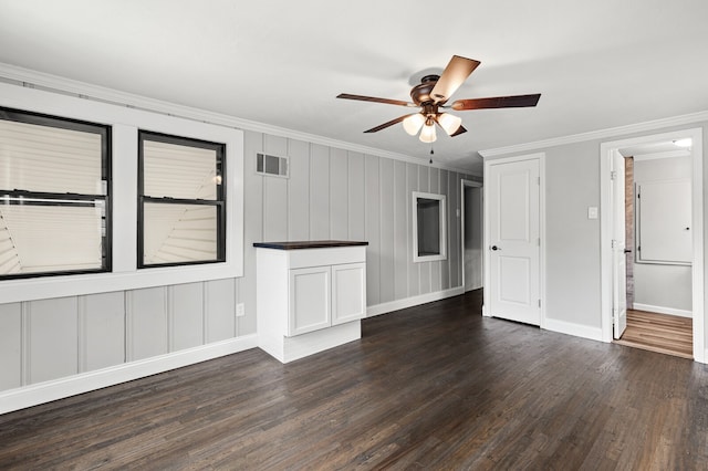 unfurnished living room featuring ornamental molding, dark wood-type flooring, and ceiling fan