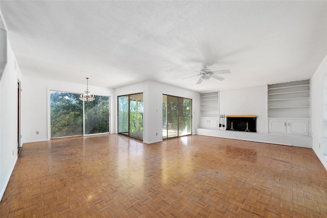 unfurnished living room with parquet flooring, ceiling fan with notable chandelier, a textured ceiling, and built in shelves