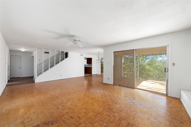 unfurnished living room with ceiling fan with notable chandelier and parquet flooring