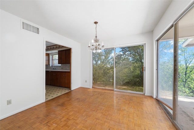 unfurnished dining area with sink, light parquet floors, and an inviting chandelier