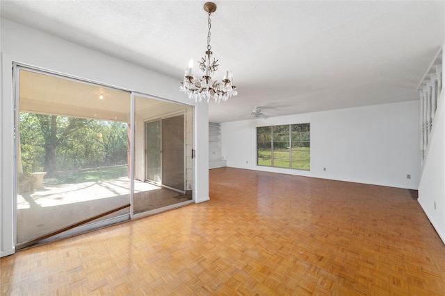 interior space with a textured ceiling, ceiling fan with notable chandelier, parquet flooring, and plenty of natural light