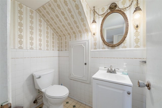 bathroom with tile patterned flooring, vanity, toilet, and tile walls