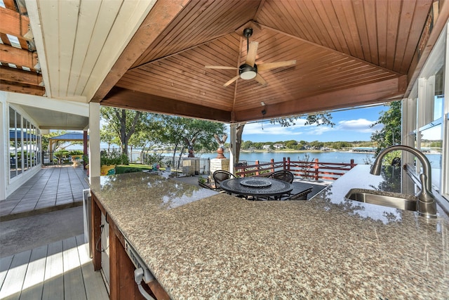 view of patio with ceiling fan, an outdoor wet bar, and a water view