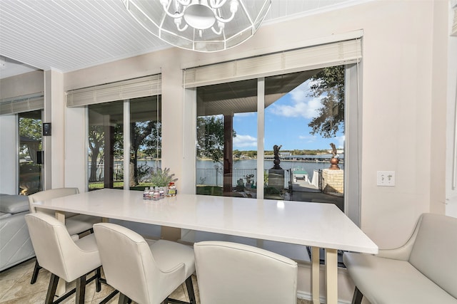 dining space with a wealth of natural light, a water view, and a chandelier