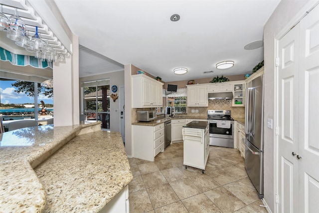 kitchen featuring light stone countertops, white cabinetry, appliances with stainless steel finishes, and a center island