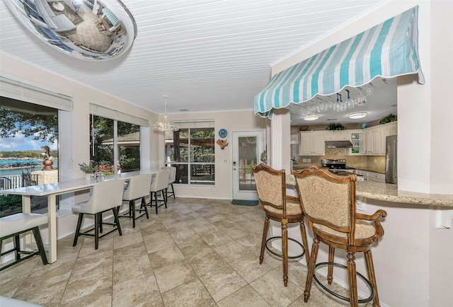 kitchen with stainless steel appliances, light stone countertops, a breakfast bar area, pendant lighting, and decorative backsplash