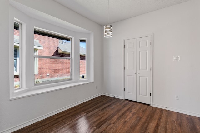 empty room with dark hardwood / wood-style floors and a textured ceiling