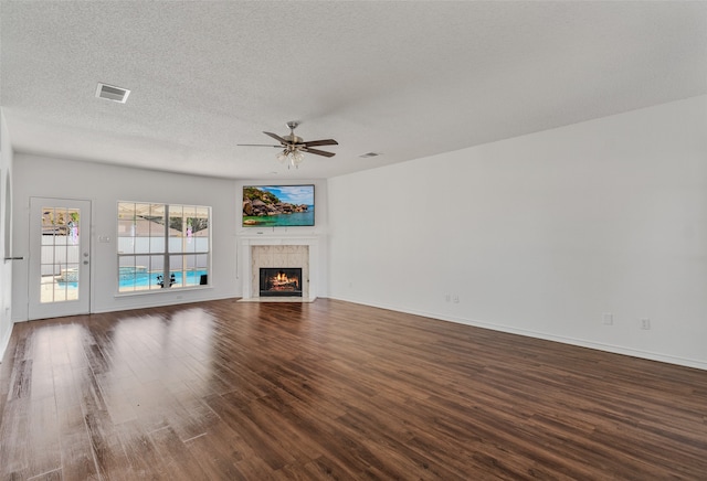 unfurnished living room with a textured ceiling, dark hardwood / wood-style floors, and ceiling fan