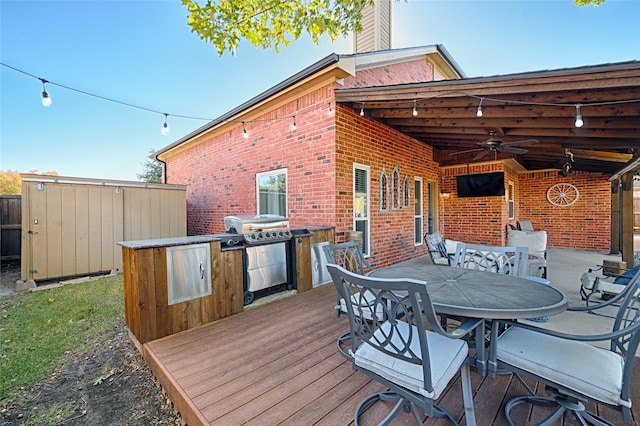 wooden terrace featuring grilling area, ceiling fan, and exterior kitchen