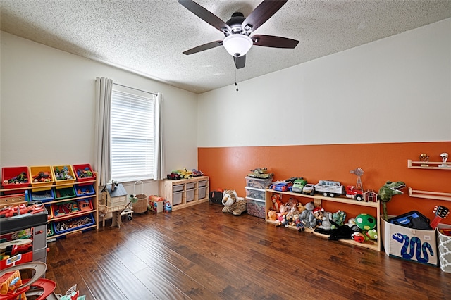 game room with ceiling fan, dark wood-type flooring, and a textured ceiling