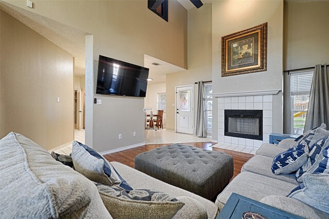 living room featuring hardwood / wood-style flooring, a high ceiling, and a tiled fireplace