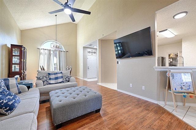 living room featuring hardwood / wood-style flooring, ceiling fan, a textured ceiling, and high vaulted ceiling