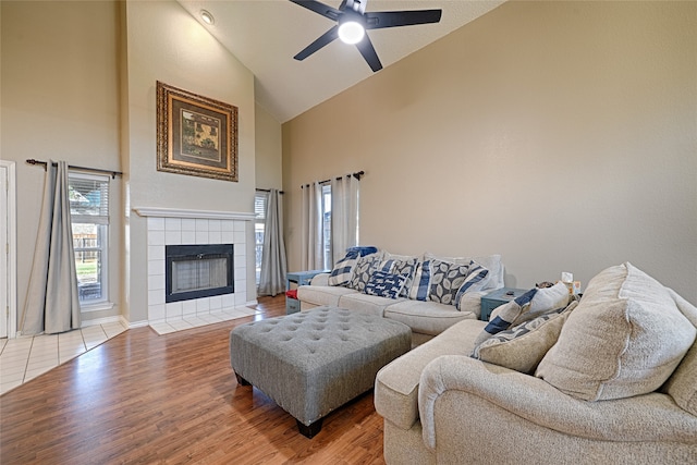 living room with a tile fireplace, hardwood / wood-style flooring, high vaulted ceiling, and ceiling fan