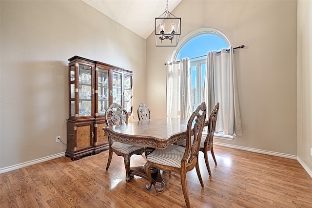 dining area with an inviting chandelier, high vaulted ceiling, and light wood-type flooring