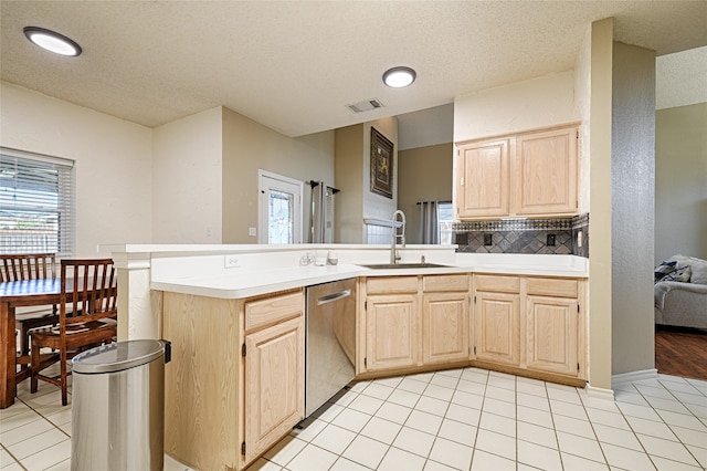 kitchen featuring kitchen peninsula, light brown cabinets, stainless steel dishwasher, and sink