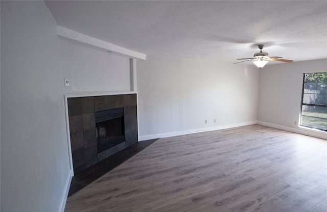 unfurnished living room featuring hardwood / wood-style floors, ceiling fan, and a tiled fireplace