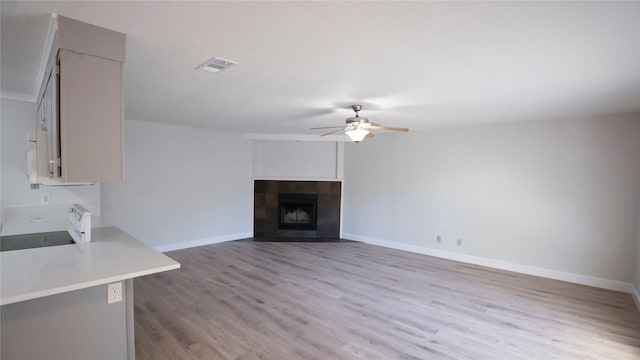 unfurnished living room featuring ceiling fan, a fireplace, and light hardwood / wood-style floors