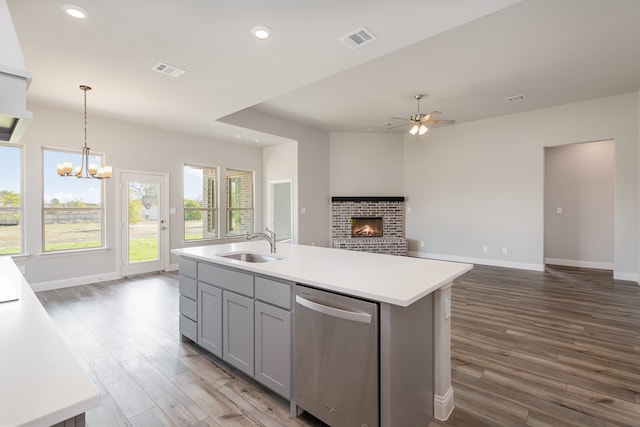 kitchen featuring a center island with sink, dark hardwood / wood-style flooring, gray cabinets, pendant lighting, and stainless steel dishwasher