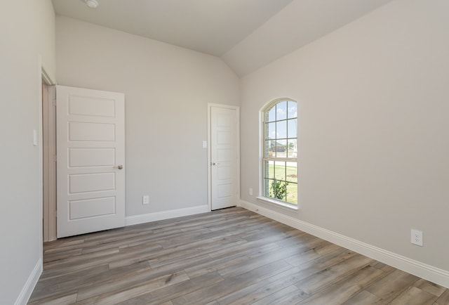 unfurnished room featuring light hardwood / wood-style floors and lofted ceiling