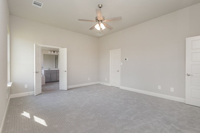 unfurnished bedroom with light colored carpet, ceiling fan, sink, and connected bathroom