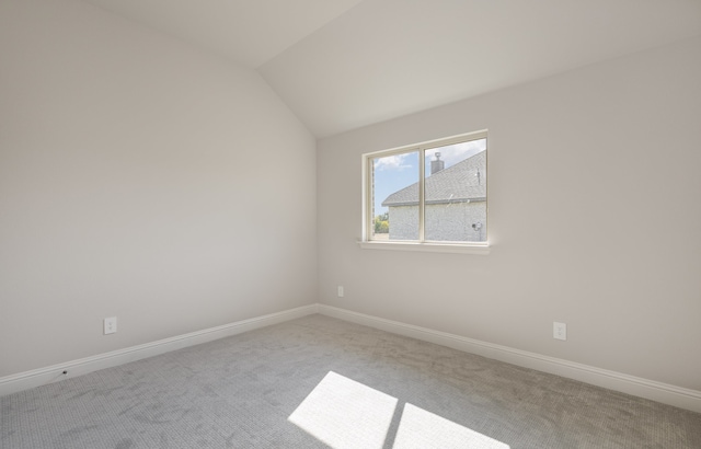 spare room with vaulted ceiling and light colored carpet